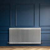 Radiador tradicional de 4 columnas en color blanco, instalado en una pared azul, con un diseño elegante y acabado liso
