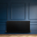 Radiador tradicional de 4 columnas en color negro, instalado en una pared azul, con un diseño elegante y líneas rectas