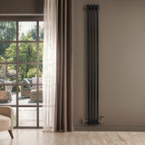Radiador tradicional de 4 columnas en color negro, instalado en una pared, con detalles dorados y un fondo de ventana luminosa
