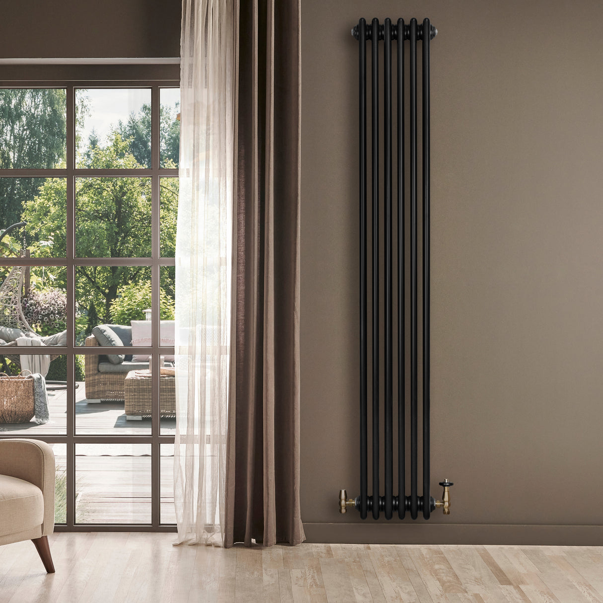 Radiador tradicional de 4 columnas en color negro, instalado en una pared, con válvula dorada y fondo de ventana iluminada