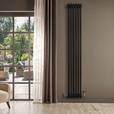 Radiador tradicional de 4 columnas en color negro, instalado en una pared, con válvula dorada y fondo de ventana iluminada