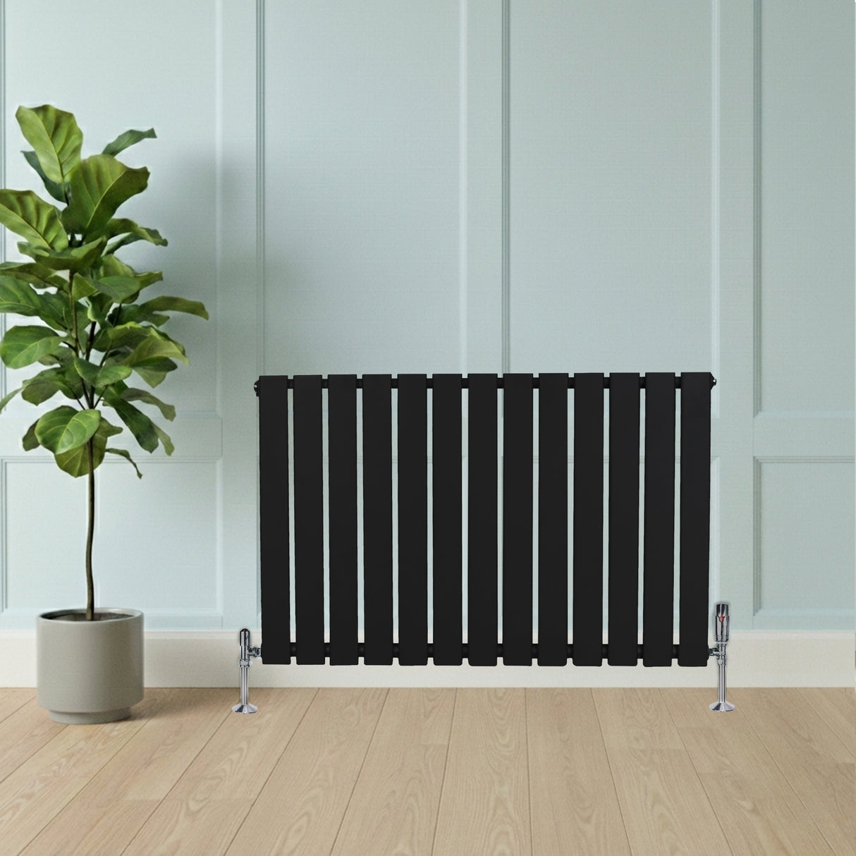 Radiador de columna única negro de 600 mm x 910 mm, con diseño moderno y elegante, colocado junto a una planta en maceta sobre suelo de madera clara