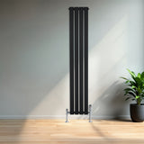 Radiador de columna única negro de 1600 mm x 280 mm, con diseño moderno y acabado liso, instalado en una pared clara junto a una planta decorativa