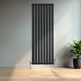 Radiador de columna única negro, 1600 mm x 560 mm, con diseño vertical y acabado liso, instalado en una pared clara junto a una planta decorativa