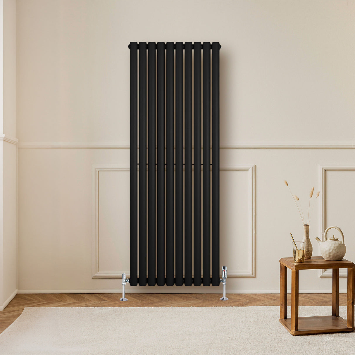 Radiador de columna ovalado negro de 1600 mm x 600 mm, con diseño elegante y acabado mate, instalado en una pared clara junto a un mueble de madera