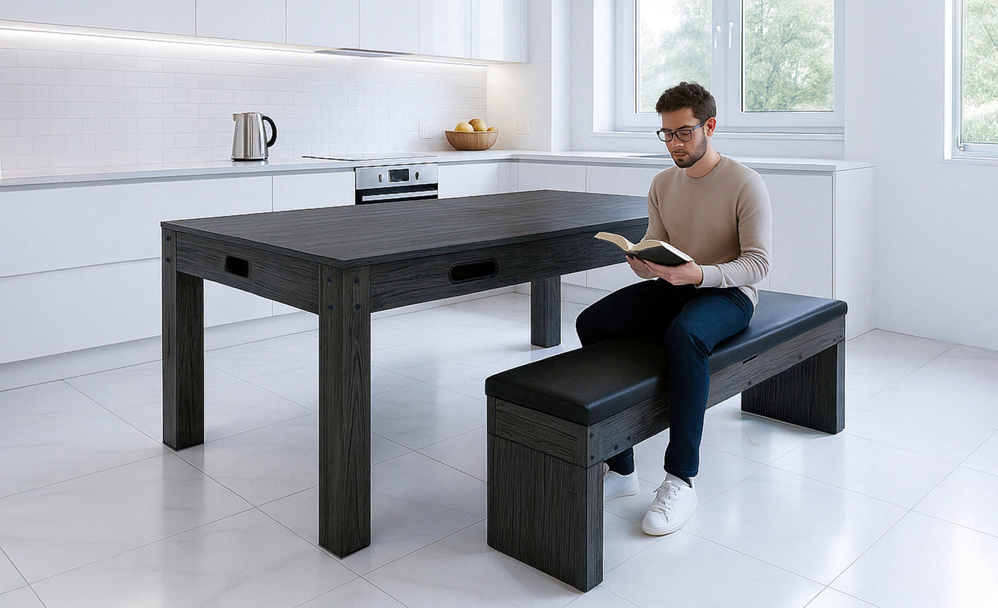 Mesa de cocina moderna de madera oscura con un hombre leyendo en un banco negro, rodeada de un ambiente luminoso y minimalista